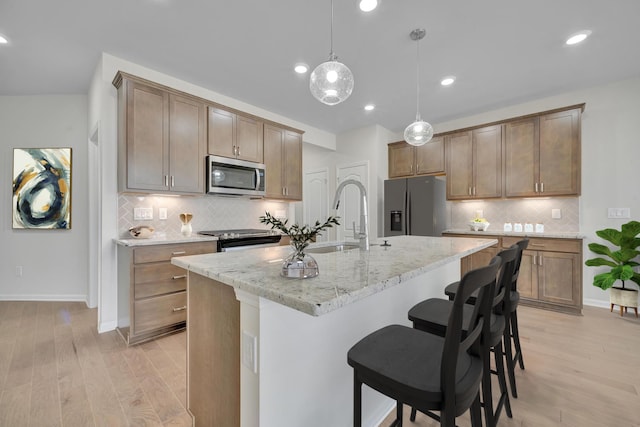 kitchen featuring decorative backsplash, a breakfast bar, a sink, and appliances with stainless steel finishes