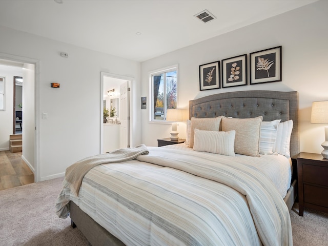 bedroom featuring light carpet and connected bathroom