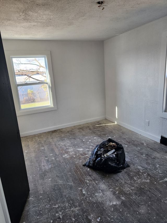 unfurnished room with a textured ceiling and dark hardwood / wood-style floors