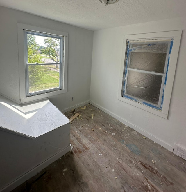 spare room featuring dark hardwood / wood-style flooring and a textured ceiling