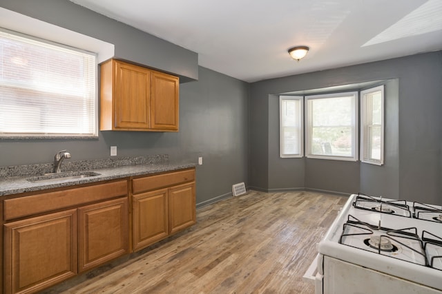 kitchen with sink, white range with gas stovetop, and light wood-type flooring