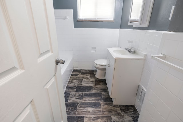 bathroom featuring vanity, toilet, tile walls, and a bathing tub