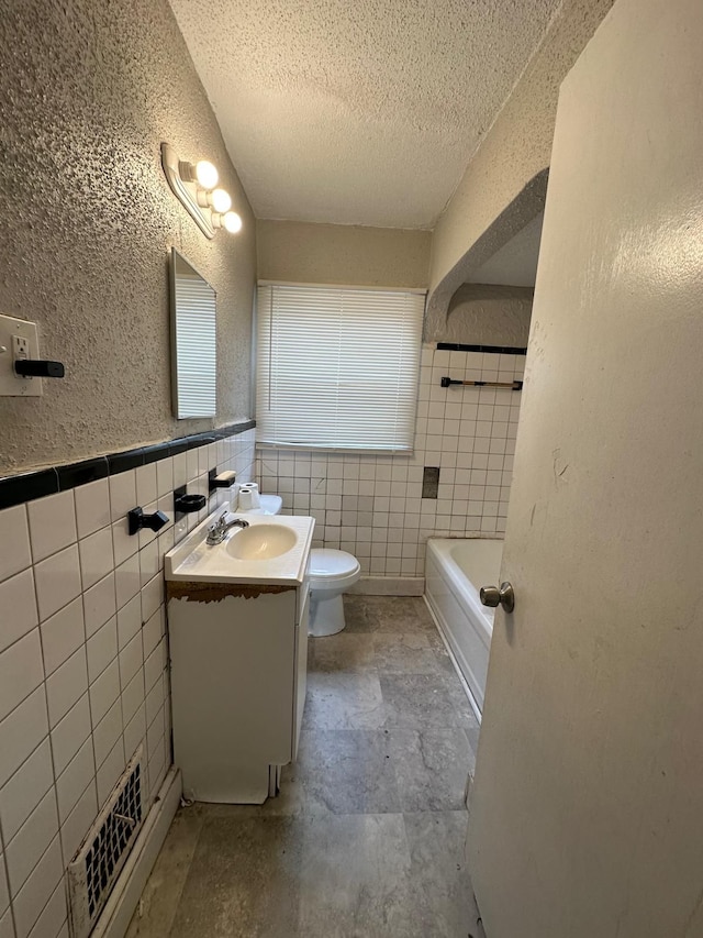 bathroom with toilet, a textured ceiling, tile walls, vanity, and a bath