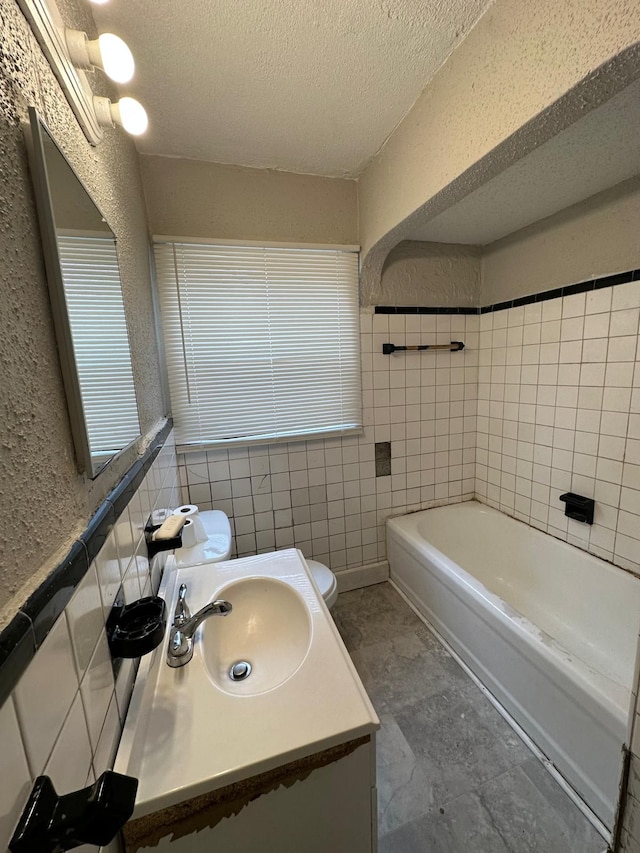 bathroom featuring tile walls, vanity, and a textured ceiling