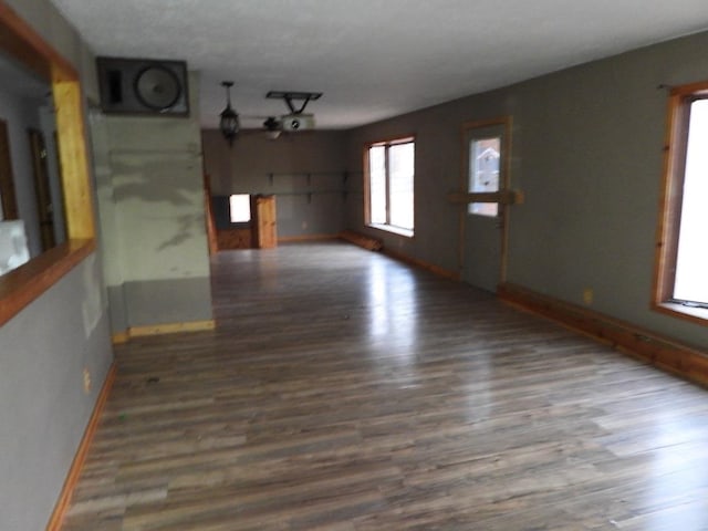 unfurnished living room featuring a wealth of natural light and dark wood-type flooring
