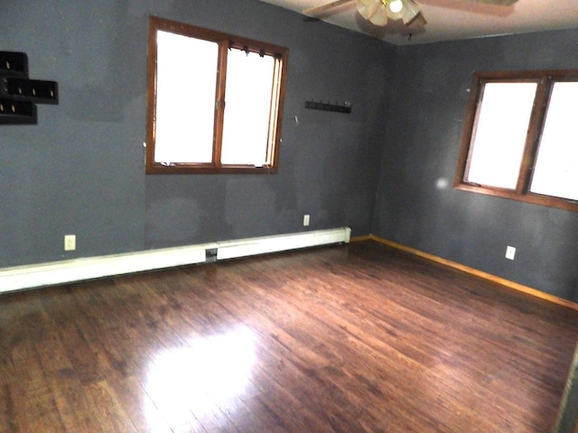 spare room featuring baseboard heating, ceiling fan, and dark wood-type flooring