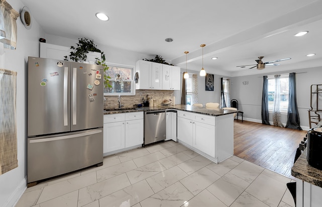 kitchen with white cabinets, dark stone countertops, kitchen peninsula, and stainless steel appliances