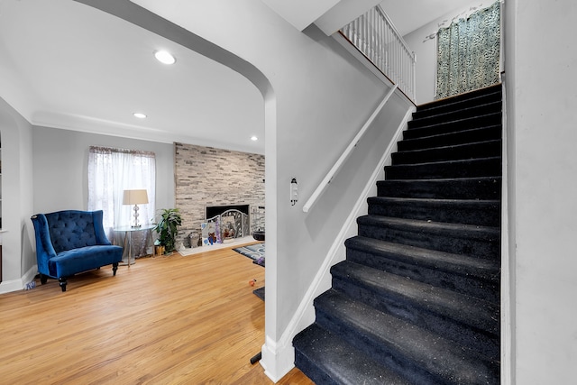 stairway featuring hardwood / wood-style floors and a fireplace