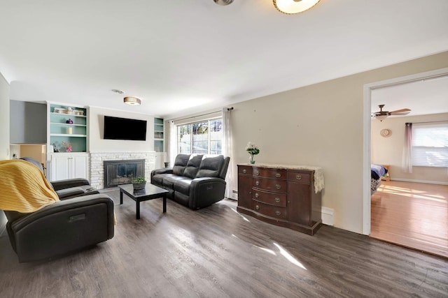 living room with plenty of natural light, dark hardwood / wood-style floors, baseboard heating, and a fireplace