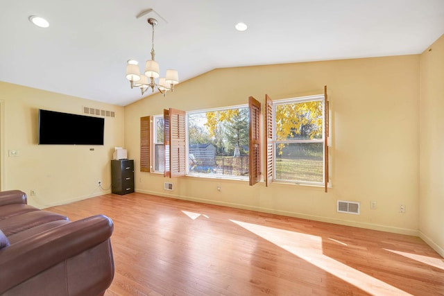 living room with light hardwood / wood-style floors, vaulted ceiling, and a notable chandelier