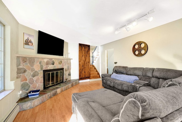 living room with a fireplace, hardwood / wood-style floors, rail lighting, and a baseboard heating unit