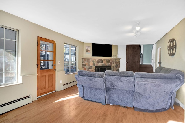 living room featuring a fireplace, hardwood / wood-style flooring, and a baseboard heating unit