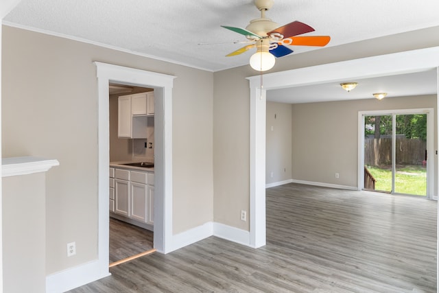 unfurnished room featuring ceiling fan, ornamental molding, a textured ceiling, and light wood-type flooring