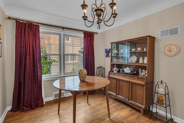 dining area with light hardwood / wood-style flooring and a notable chandelier