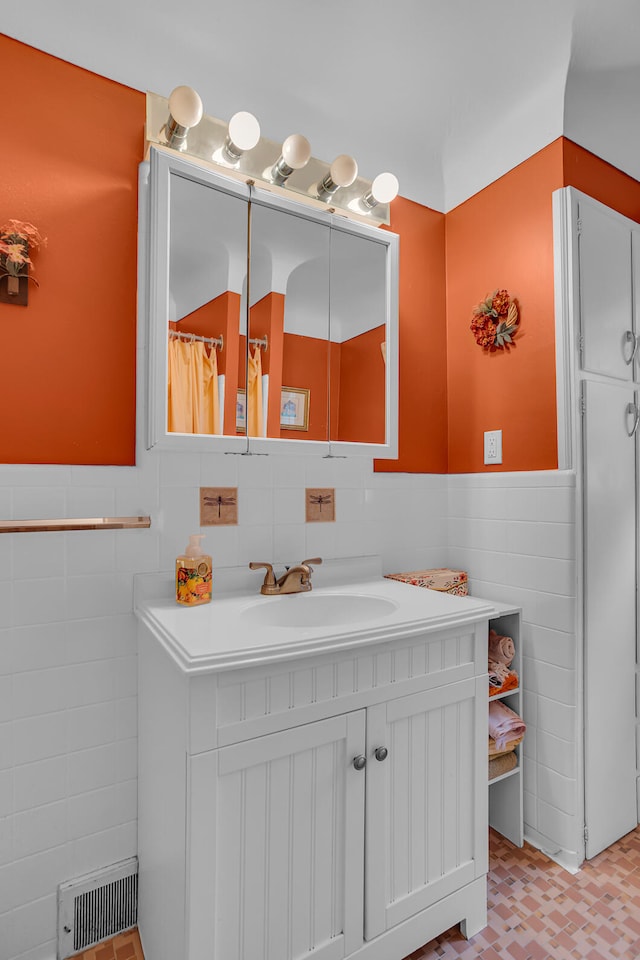 bathroom featuring vanity and tile walls