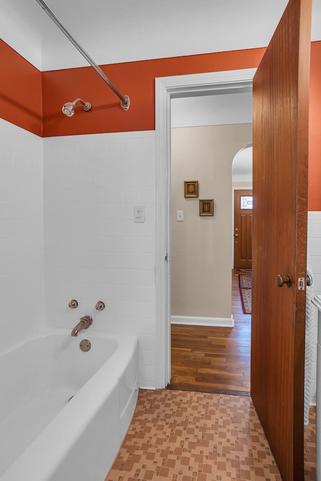 bathroom with hardwood / wood-style floors and tiled shower / bath