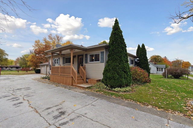 view of front of home featuring an outbuilding, a front lawn, a porch, and a garage