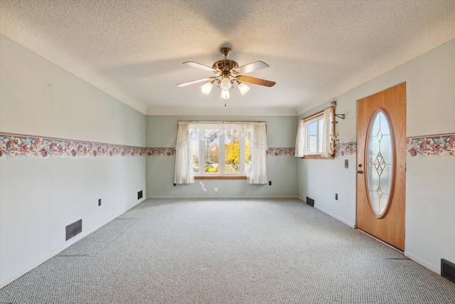 empty room with a textured ceiling, light colored carpet, and ceiling fan