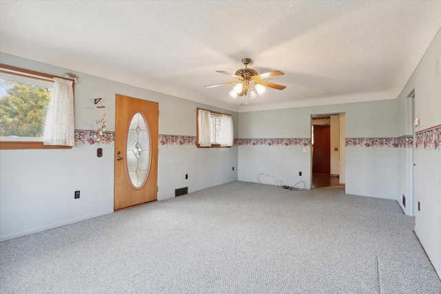 carpeted empty room featuring ceiling fan and a textured ceiling