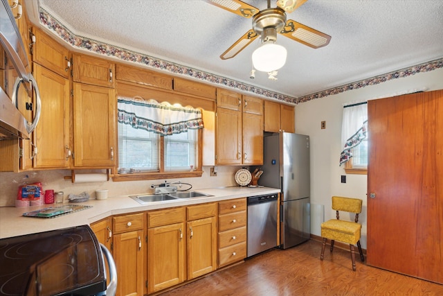 kitchen with sink, ceiling fan, a textured ceiling, appliances with stainless steel finishes, and dark hardwood / wood-style flooring