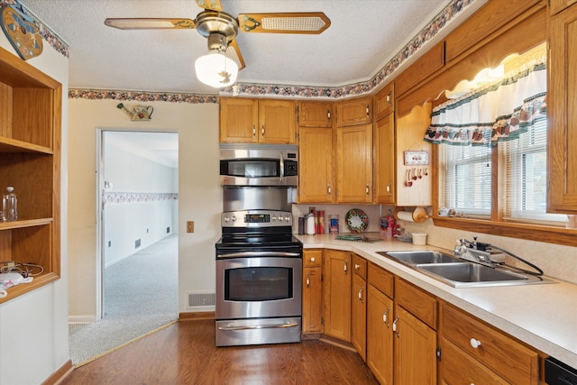 kitchen with ceiling fan, sink, dark hardwood / wood-style flooring, a textured ceiling, and appliances with stainless steel finishes