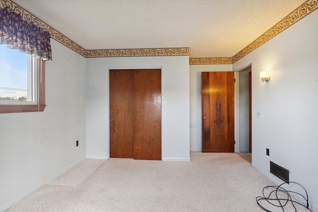 unfurnished bedroom with carpet, a textured ceiling, and a closet