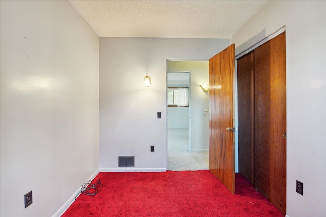 carpeted empty room featuring a textured ceiling