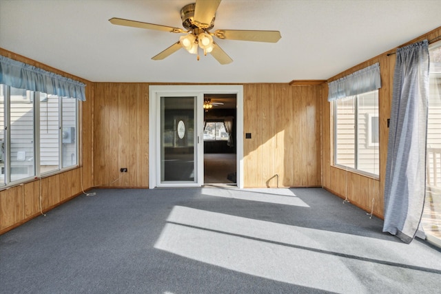 carpeted empty room featuring ceiling fan and wooden walls