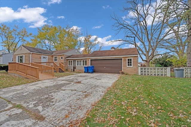 rear view of property featuring a lawn, a garage, and a deck