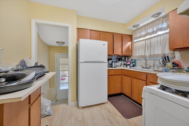 kitchen with plenty of natural light, light hardwood / wood-style floors, white appliances, and sink