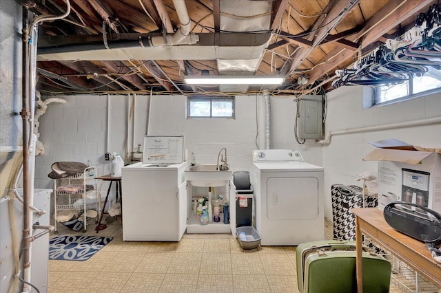 clothes washing area featuring washing machine and dryer, electric panel, a healthy amount of sunlight, and sink