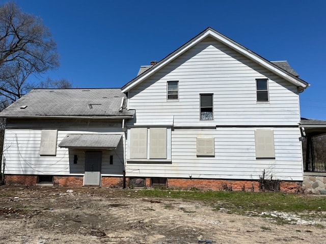 rear view of house featuring a chimney and roof with shingles