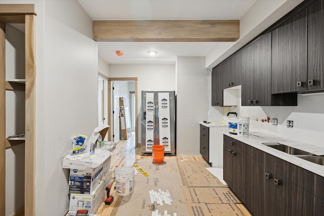 800 NW Douglas St, Grand Rapids, MI 49505 - kitchen featuring freestanding refrigerator, light countertops, dark brown cabinetry, a sink, and beam ceiling