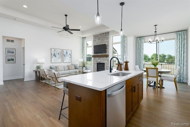 kitchen with stainless steel dishwasher, a healthy amount of sunlight, light wood-type flooring, and an island with sink