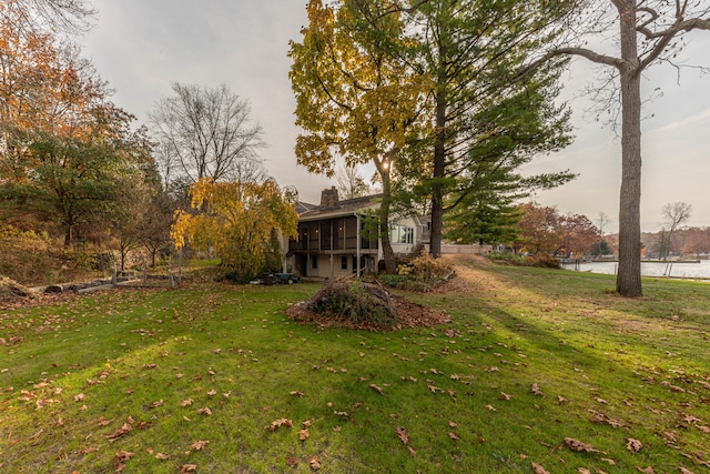 view of yard with a sunroom and a water view