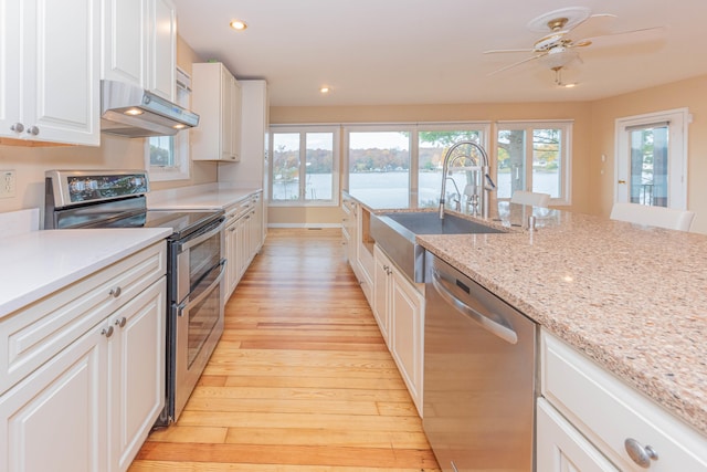 kitchen with appliances with stainless steel finishes, ceiling fan, sink, white cabinets, and light hardwood / wood-style floors