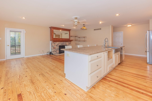 kitchen featuring a center island with sink, light hardwood / wood-style flooring, ceiling fan, and sink