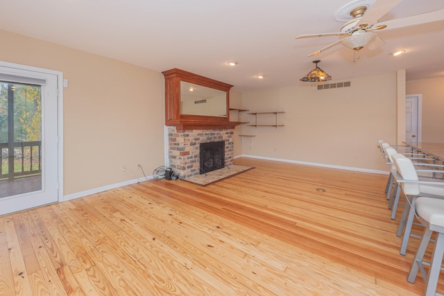 unfurnished living room with a fireplace, light hardwood / wood-style floors, and ceiling fan