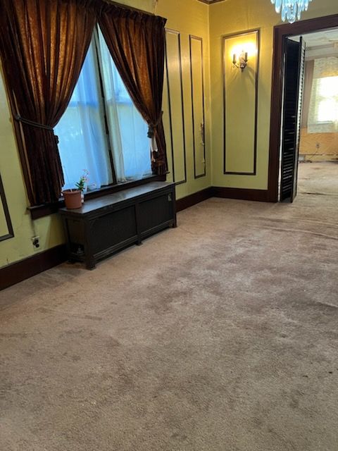 cinema room with plenty of natural light, light colored carpet, and an inviting chandelier