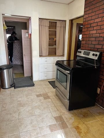 kitchen featuring stainless steel range with electric cooktop and brick wall