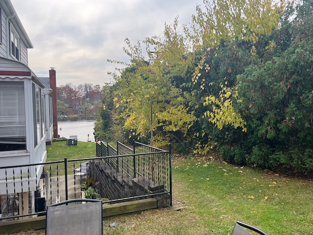 view of yard with central air condition unit and a water view