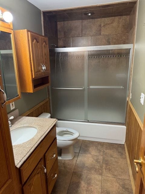 full bathroom with vanity, toilet, wooden walls, and enclosed tub / shower combo