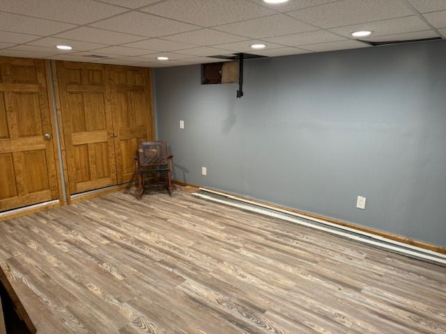 interior space featuring a paneled ceiling and light hardwood / wood-style floors