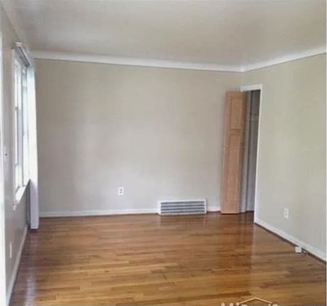 spare room with a healthy amount of sunlight, wood-type flooring, and ornamental molding