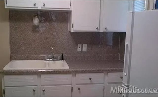 kitchen featuring white cabinets, backsplash, and sink