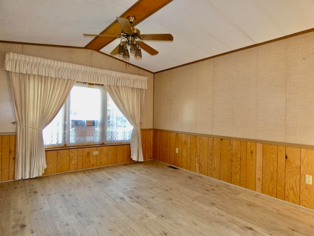 empty room featuring ceiling fan, light wood-type flooring, wooden walls, and vaulted ceiling