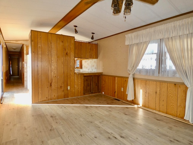 interior space with wood walls, ceiling fan, light hardwood / wood-style floors, and vaulted ceiling with beams