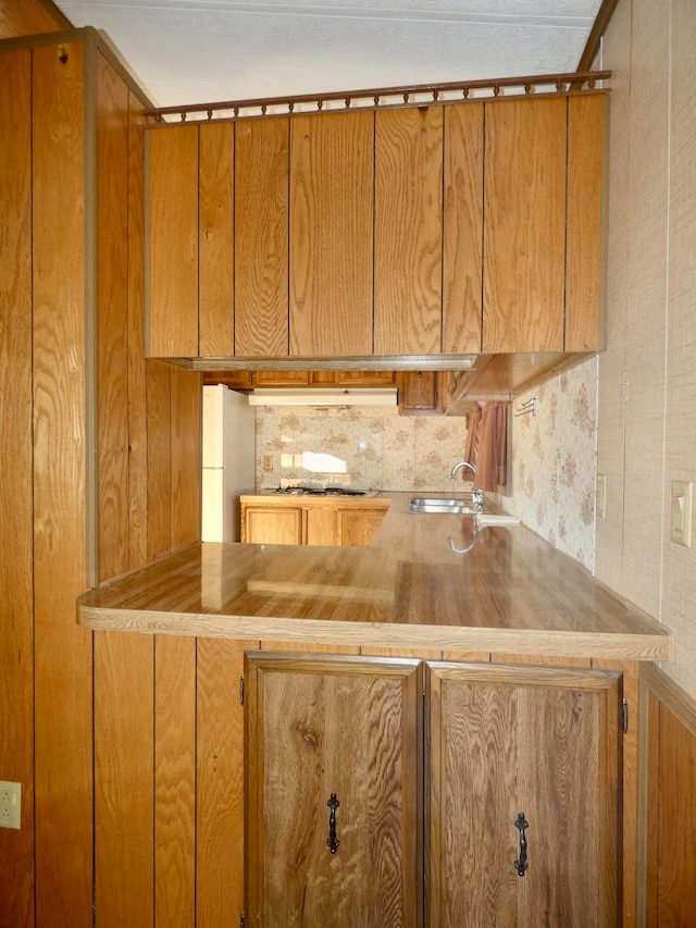 kitchen featuring gas cooktop, white refrigerator, backsplash, and sink