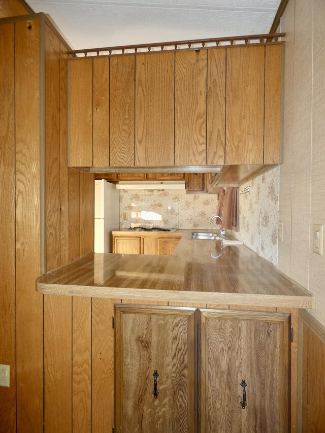 3924 W Jefferson Ave Unit 3924, Trenton, MI 48183 - kitchen with brown cabinetry, a sink, gas cooktop, and under cabinet range hood