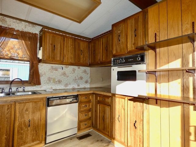 kitchen featuring backsplash, sink, white appliances, and light hardwood / wood-style flooring